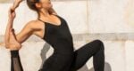 Woman wearing black in yoga pose outside