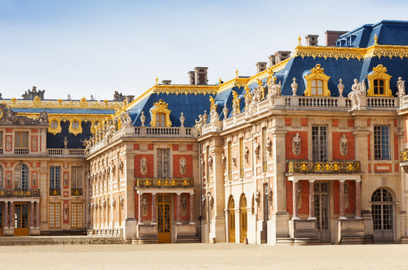 Exterior view of one wing of the Palace of Versailles made of red brick with a blue roof