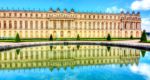 An exterior view of the Palace of Versailles with a pool of water in front of it