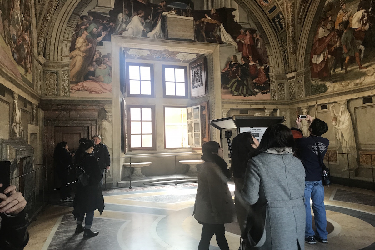 tourists looking at paintings inside the Vatican