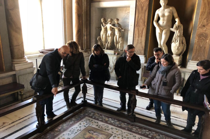 a tour group looking at a mosaic on the floor