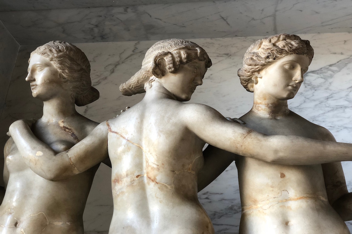 an ancient statue of 3 women