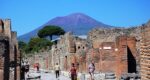 people walking on the streets in Pompeii with Vesuvius in the background