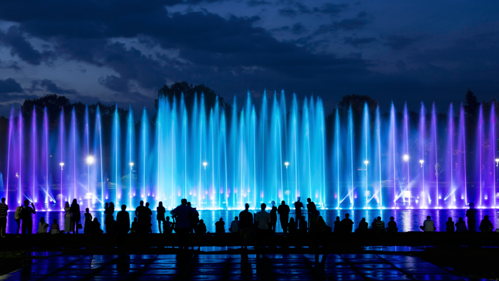 a water display of many fountains lit up blue and purple at night