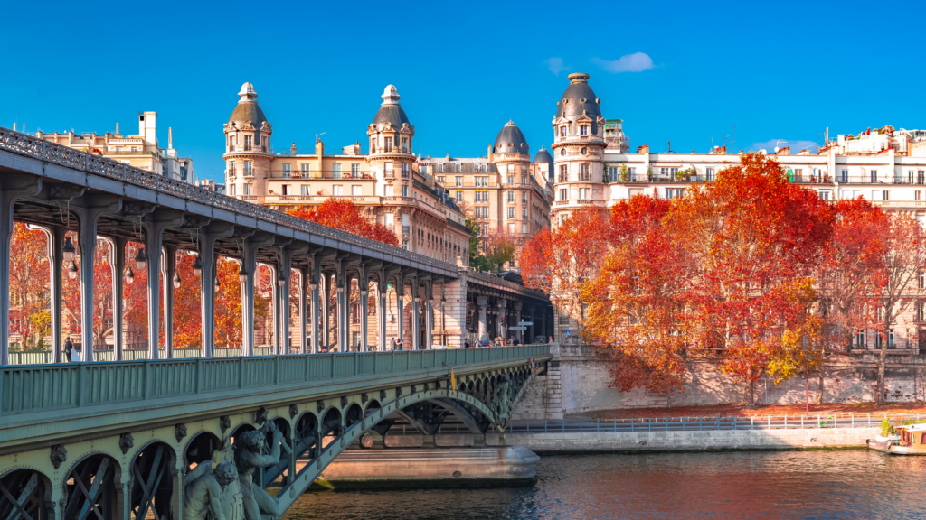 A bridge across the river Seine, red autumn trees and a historic building