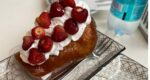 a cake covered in cream and raspberries