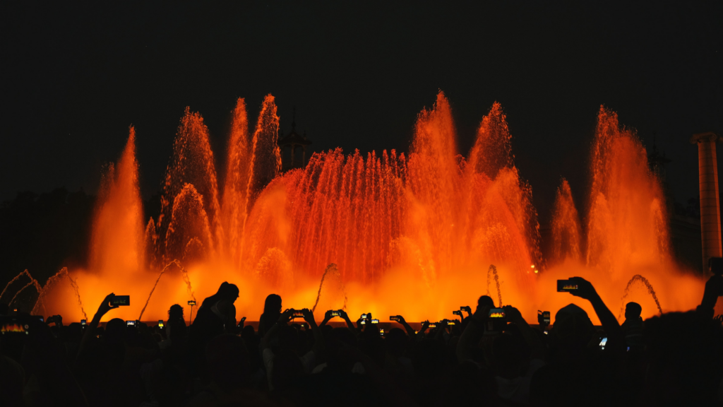 A fountain in Barcelona lit red and orange at night