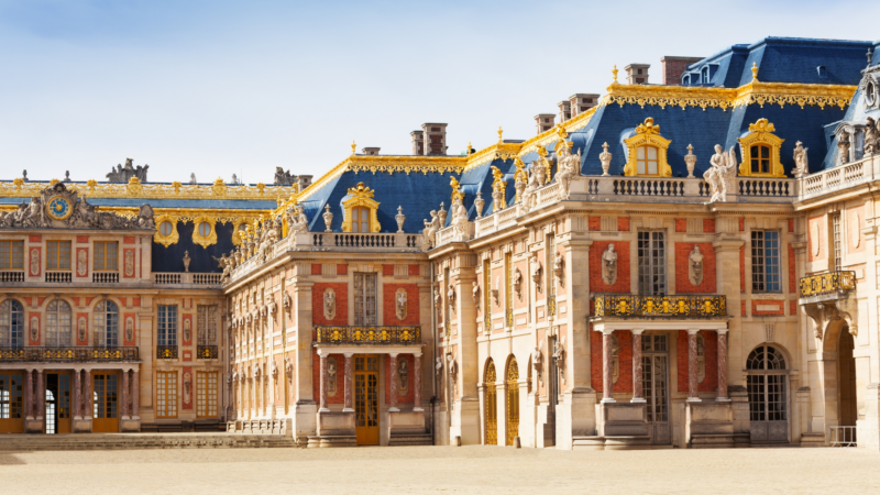 Exterior view of one wing of the Palace of Versailles made of red brick with a blue roof