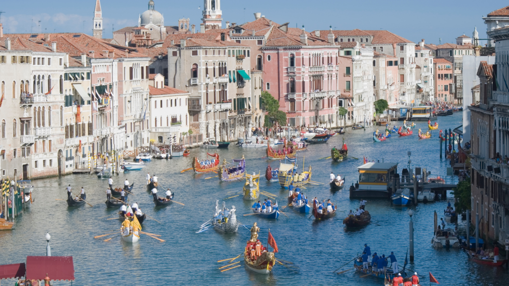 Traditional boats with flags sailing along a canal in Venice