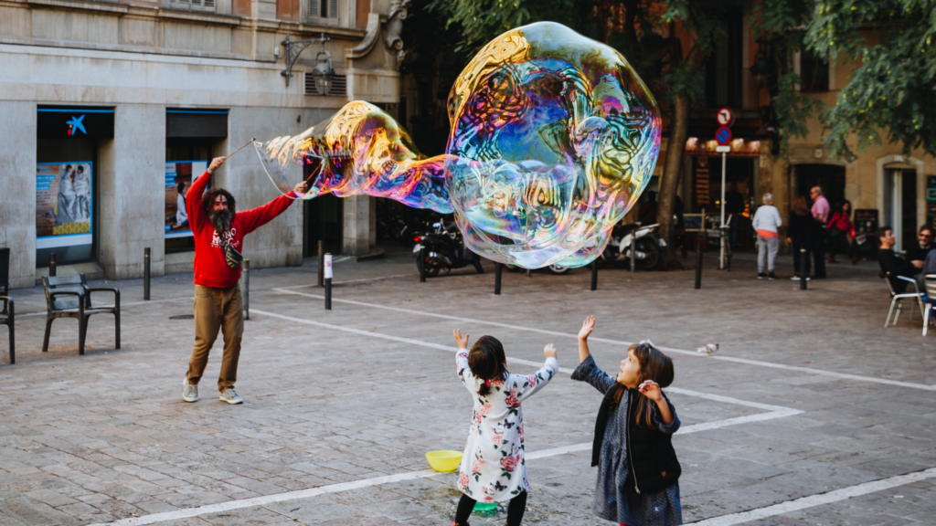 2 children watching a street performer with a large bubble in Barcelona