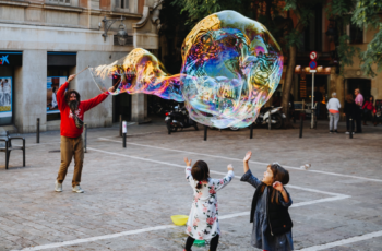 2 children watching a street performer with a large bubble