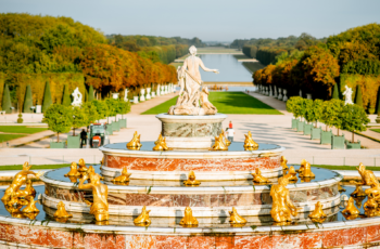 A grand fountain in the Gardens of Versailles with gold figures and many frogs