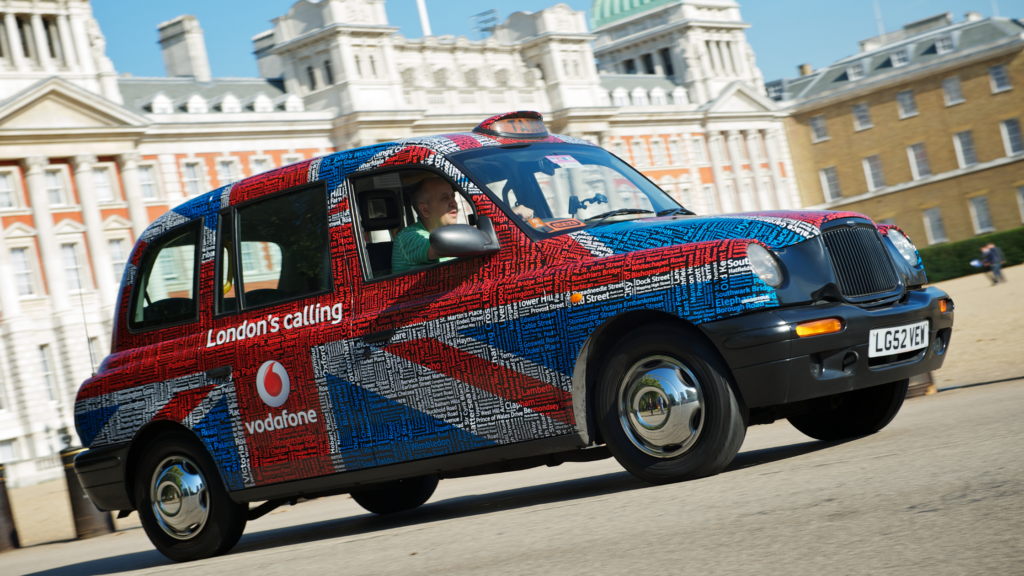 a taxi with the Union Jack painted on the side, driving through London