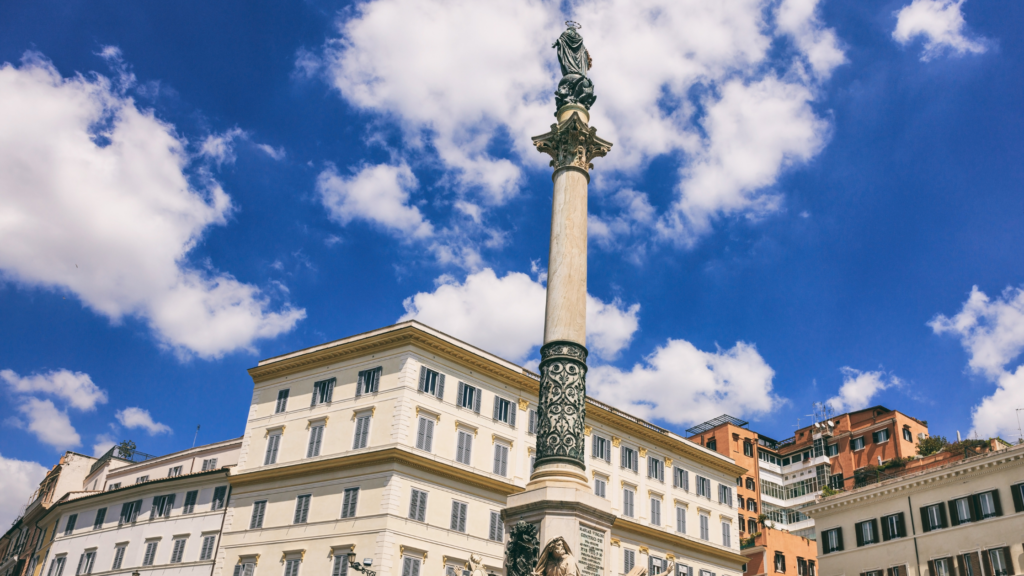 a tall column with a statue against a cloudy blue sky